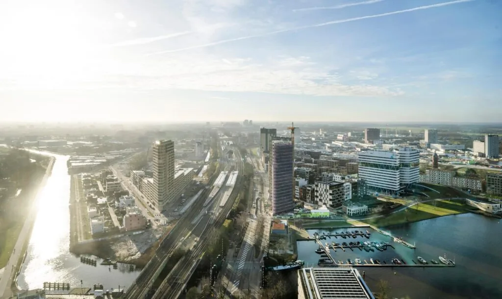 Luchtfoto van Amstelplein in Amsterdam met zicht op kantoorgebouwen, treinsporen en een jachthaven aan het water.