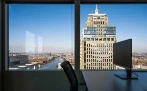 Uitzicht vanuit een kantoor op het Amstelplein in Amsterdam met een groot kantoorgebouw en de Amstel in beeld.