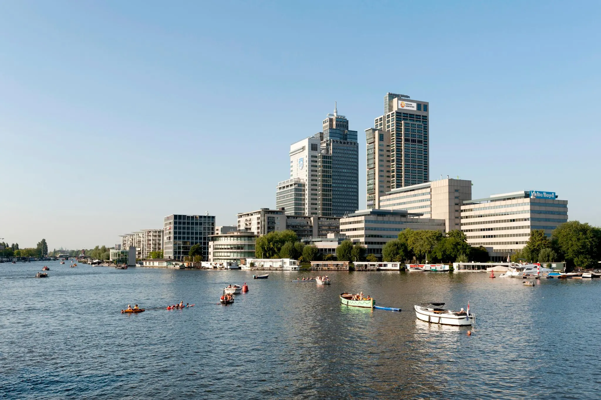 Uitzicht op het Amstelplein in Amsterdam met kantoorgebouwen en boten op de Amstel.