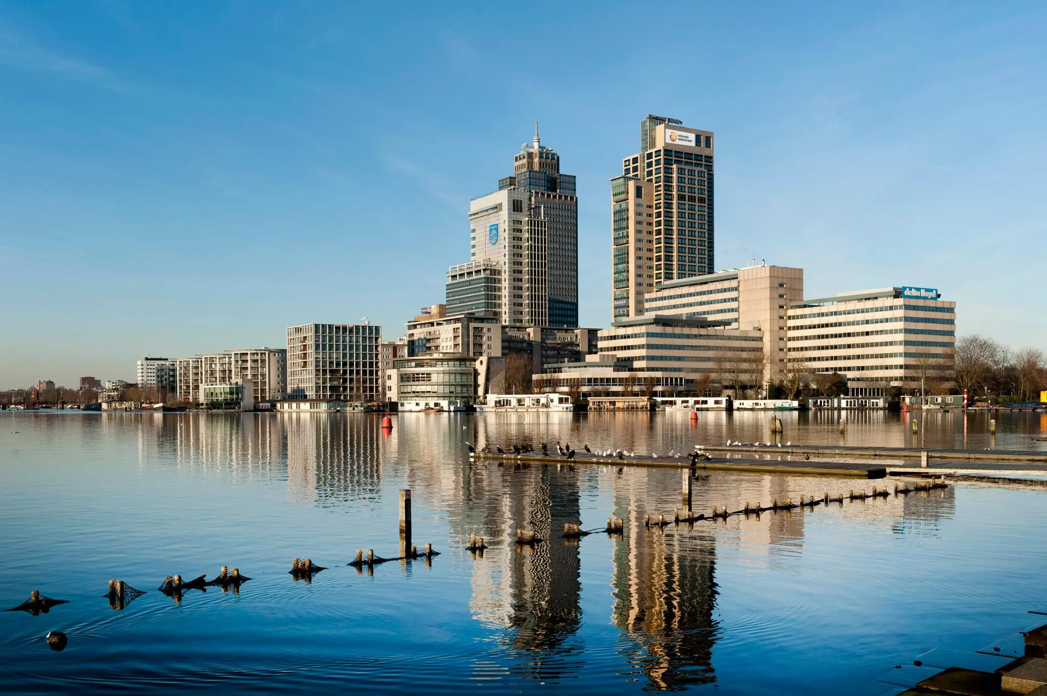 Uitzicht op de moderne kantoorgebouwen aan het Amstelplein in Amsterdam, weerspiegeld in de Amstel.
