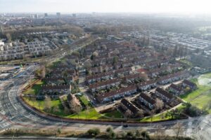 Luchtfoto van de Amstelpleinbuurt in Amsterdam met rijen roodbruine eengezinswoningen omgeven door groenstroken en wegen.