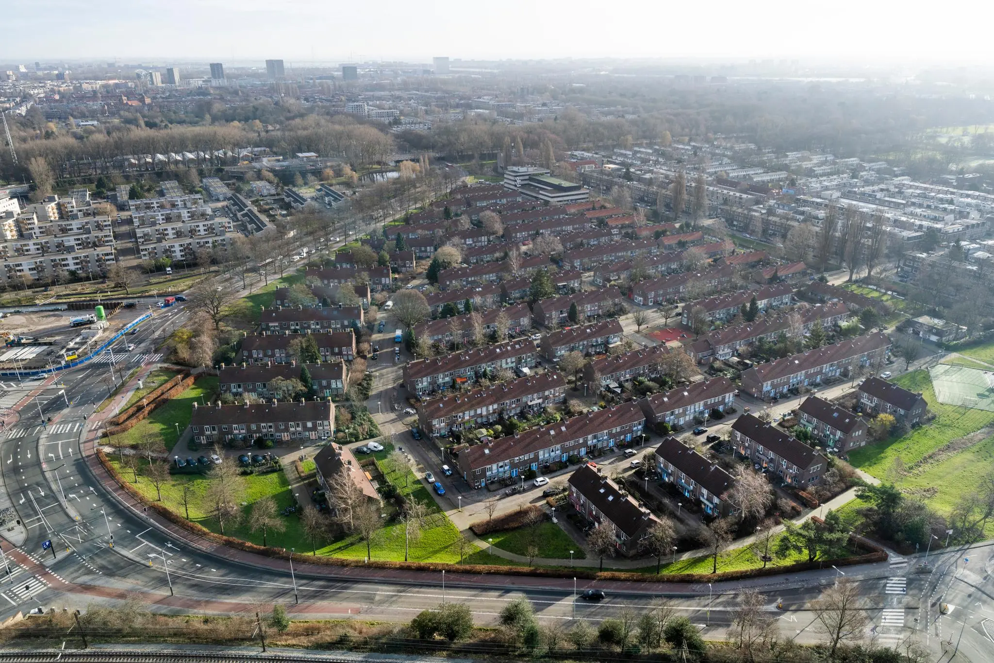 Luchtfoto van de Amstelpleinbuurt in Amsterdam met rijen roodbruine eengezinswoningen omgeven door groenstroken en wegen.
