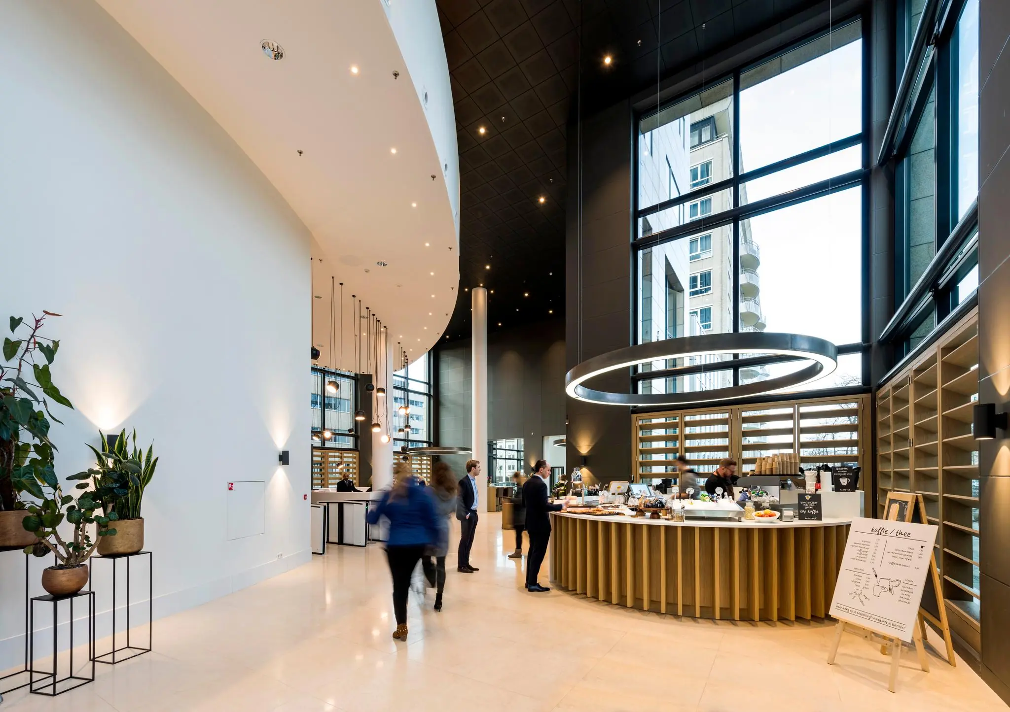 Moderne lobby met hoog plafond en een koffiebar in het gebouw aan het Amstelplein.
