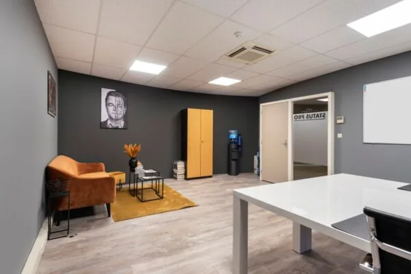 Moderne kantoorruimte met een zitgedeelte, kast, waterkoeler en een deur naar "STATUS PRO".