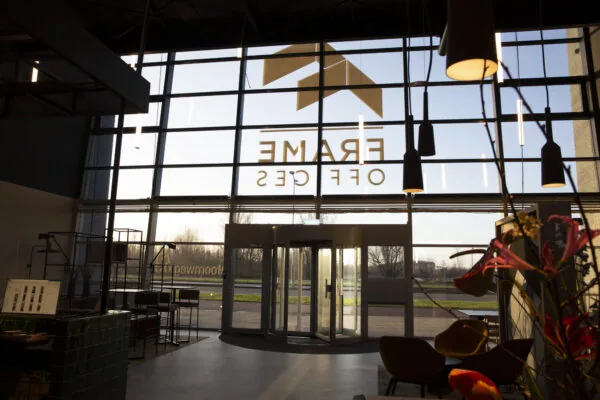 Inkomhal van Frame Offices aan de Atoomweg met draaideur, designverlichting en zitgedeelte bij een glazen gevel.