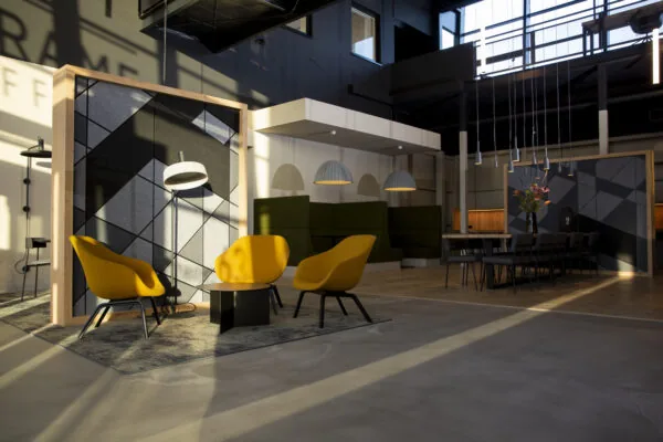 Moderne, sfeervol verlichte kantoorruimte aan de Atoomweg met gele stoelen, een zitgedeelte en een lange vergadertafel.