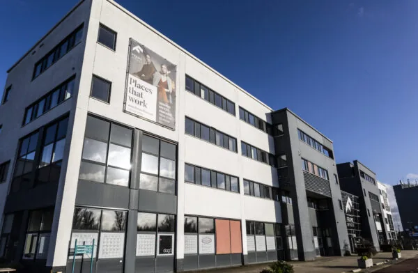 Kantoorgebouw aan de Atoomweg met reclamebanner voor Frame Offices onder een heldere blauwe lucht.