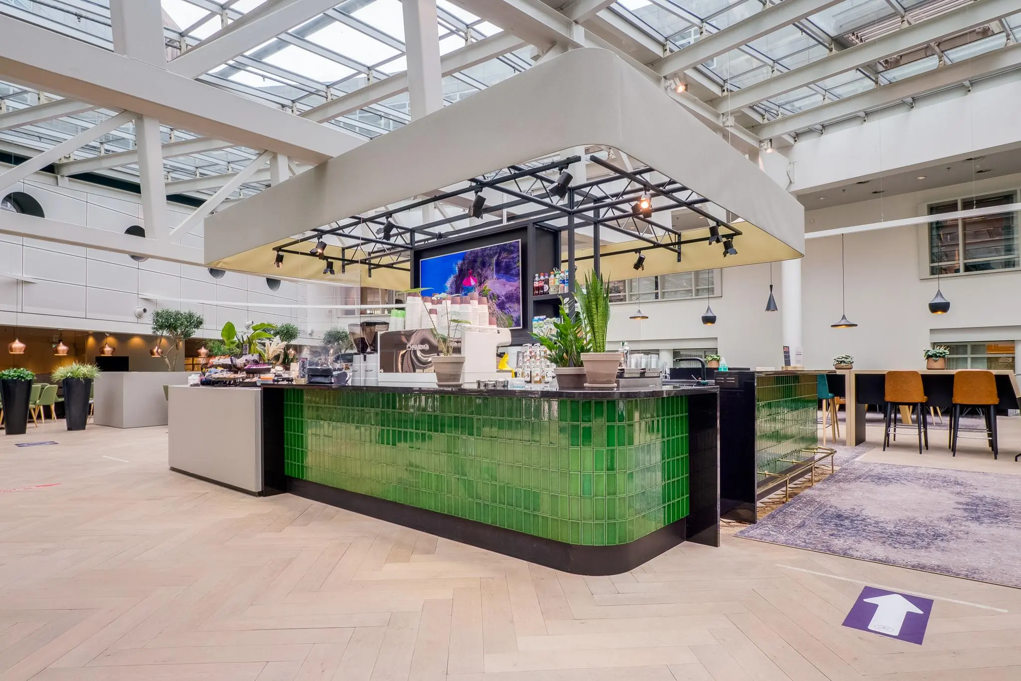 Moderne koffie- en snackbar met groene tegels in een licht atrium aan de Winthontlaan.