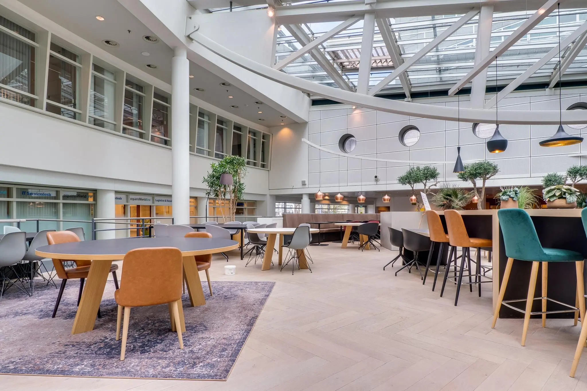 Modern ingerichte kantoorruimte aan de Winthontlaan met diverse zitplaatsen, grote raampartijen en groene accenten.