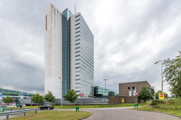 Hoog kantoorgebouw aan het Herculesplein in Utrecht met wolkenlucht op de achtergrond.