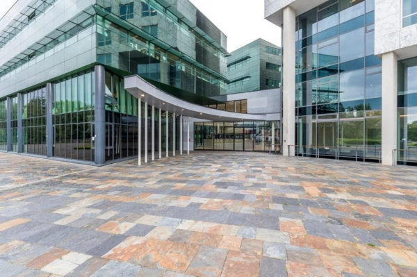 Moderne glazen kantoorgebouw aan het Herculesplein met brede entree en betegeld plein.