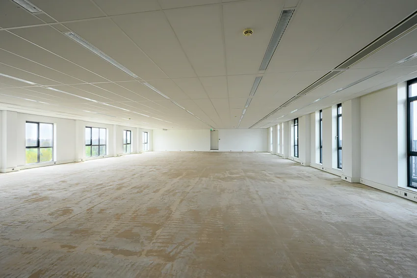 Leeg, ruim en licht kantoorinterieur aan de Haastrechtstraat met grote ramen en systeemplafond.