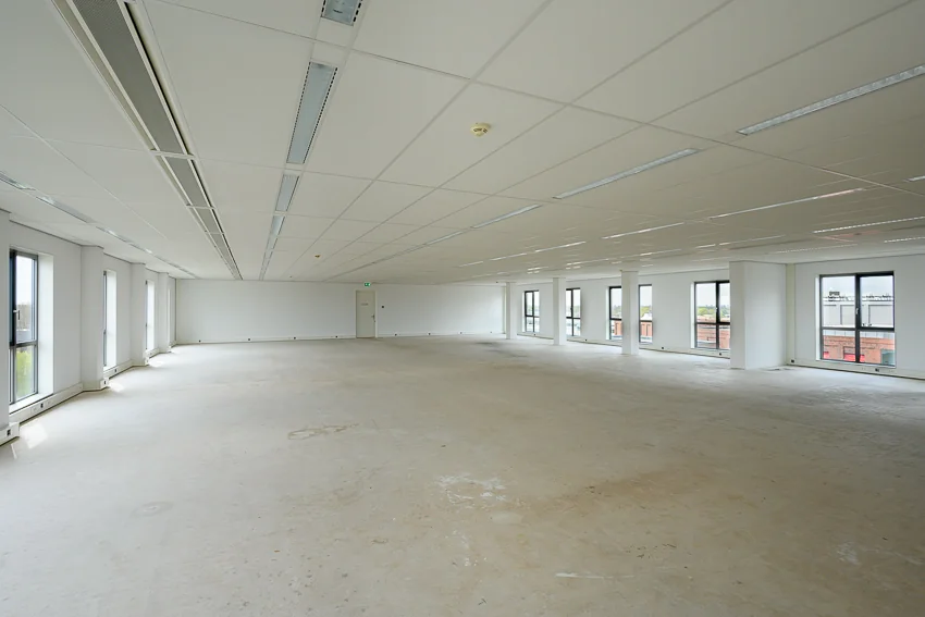 Lege kantoorruimte aan de Haastrechtstraat met witte muren, systeemplafond en grote ramen.