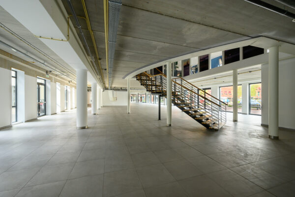 Leeg modern bedrijfspand aan de Haastrechtstraat met grote ramen en een centrale trap naar de bovenverdieping.