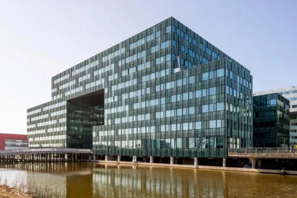 Modern kantoorgebouw aan de Herikerbergweg in Amsterdam-Zuidoost, met glazen gevel en gelegen aan het water.