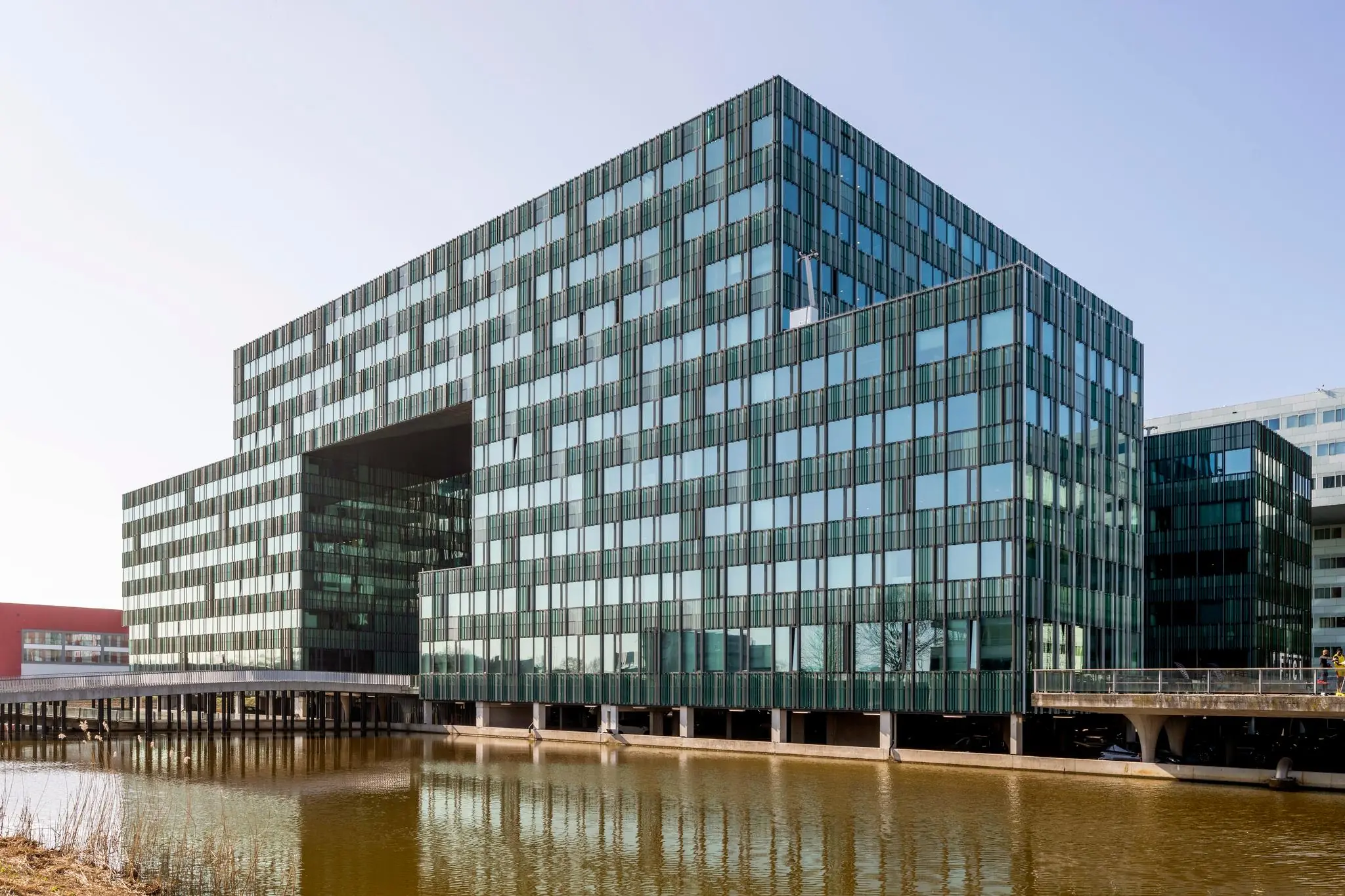 Modern kantoorgebouw aan de Herikerbergweg in Amsterdam-Zuidoost, met glazen gevel en gelegen aan het water.