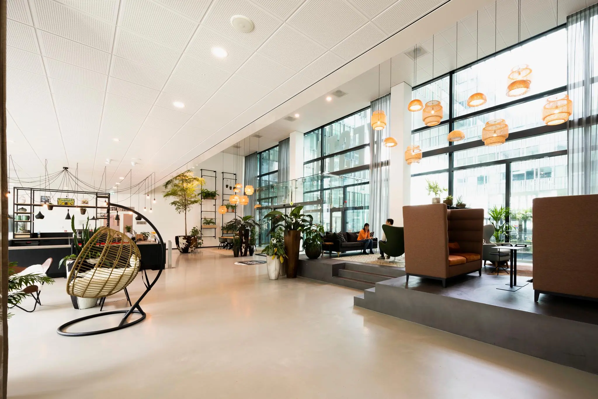 Moderne en lichte kantoorlobby aan de Herikerbergweg met designmeubels, planten en grote ramen.