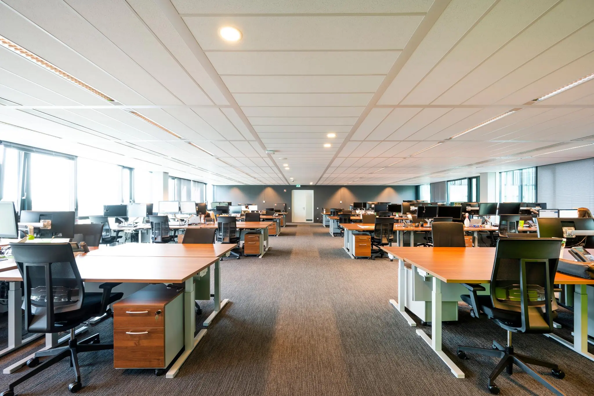 Moderne open kantoortuin aan de Herikerbergweg met rijen bureaus en ergonomische bureaustoelen.