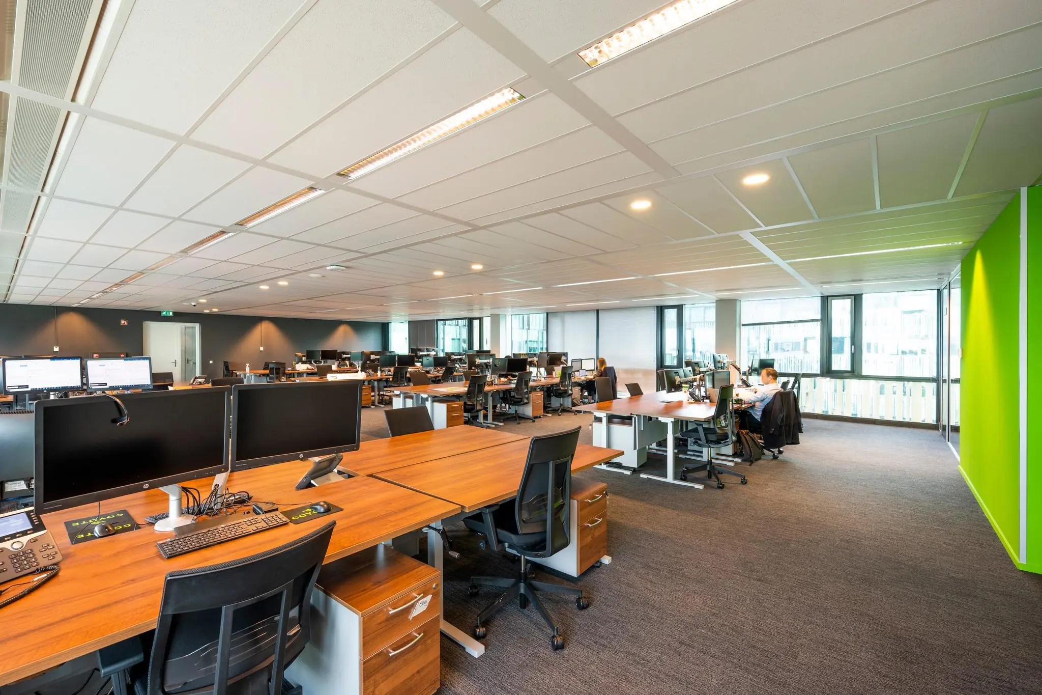Moderne open kantoorruimte aan de Herikerbergweg met bureaus, computers en grote ramen.