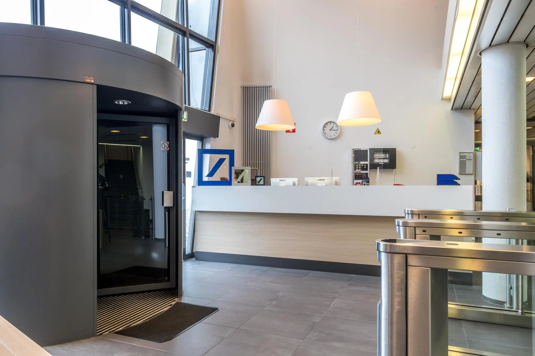 Moderne receptiebalie met toegangspoortjes en een draaideur in een kantoorgebouw aan de Lichtenauerlaan.