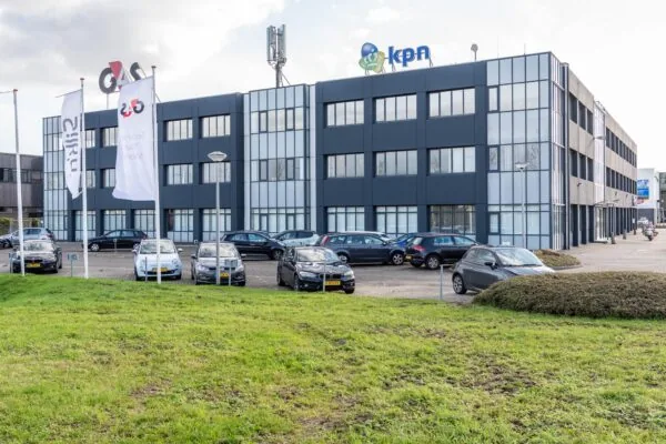 Kantoorpand met KPN- en G4S-logo's op de gevel en geparkeerde auto's op de voorgrond.