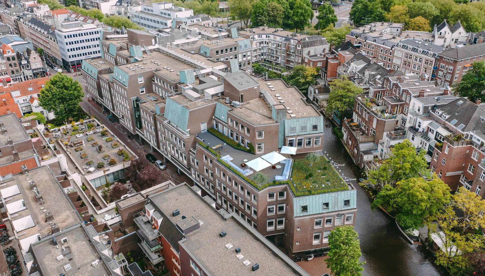 Luchtfoto van gebouwen aan de Vijzelgracht in Amsterdam met daktuinen en een aangrenzende gracht.