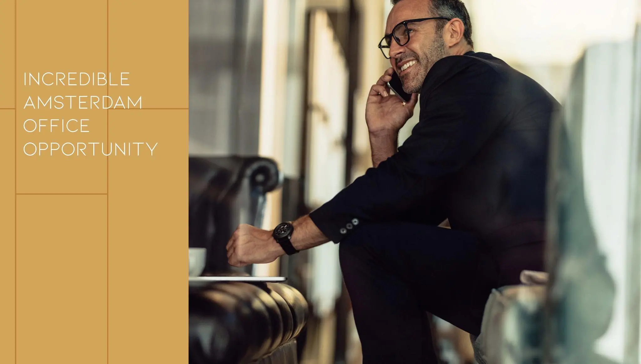 Zakelijke man in een modern kantoor aan de Vijzelgracht in Amsterdam, glimlachend terwijl hij telefoneert.