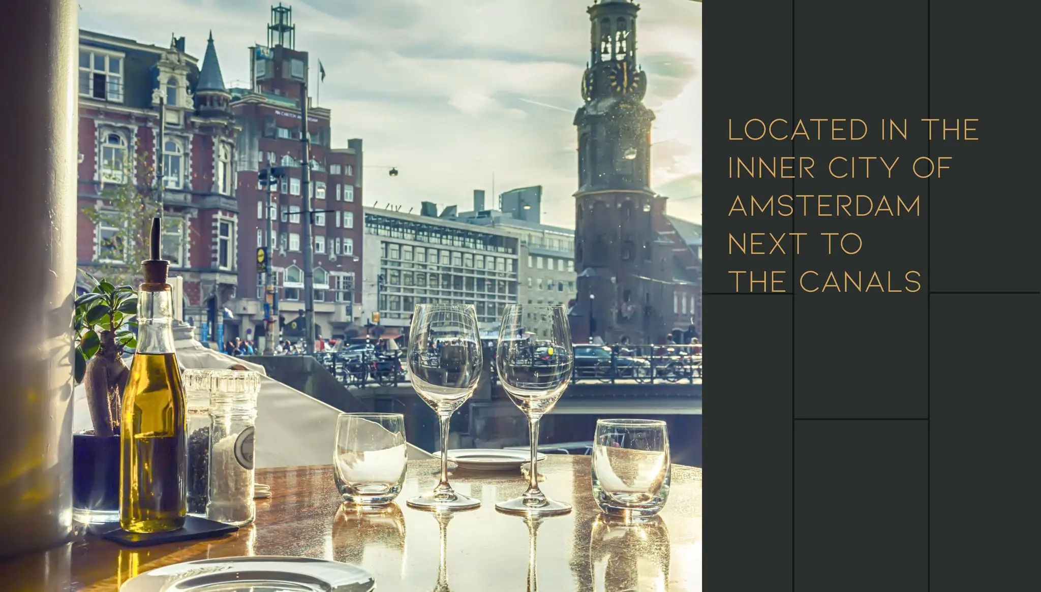 Gedekte tafel met wijnglazen in een restaurant met uitzicht op de Vijzelgracht en Munttoren in Amsterdam.