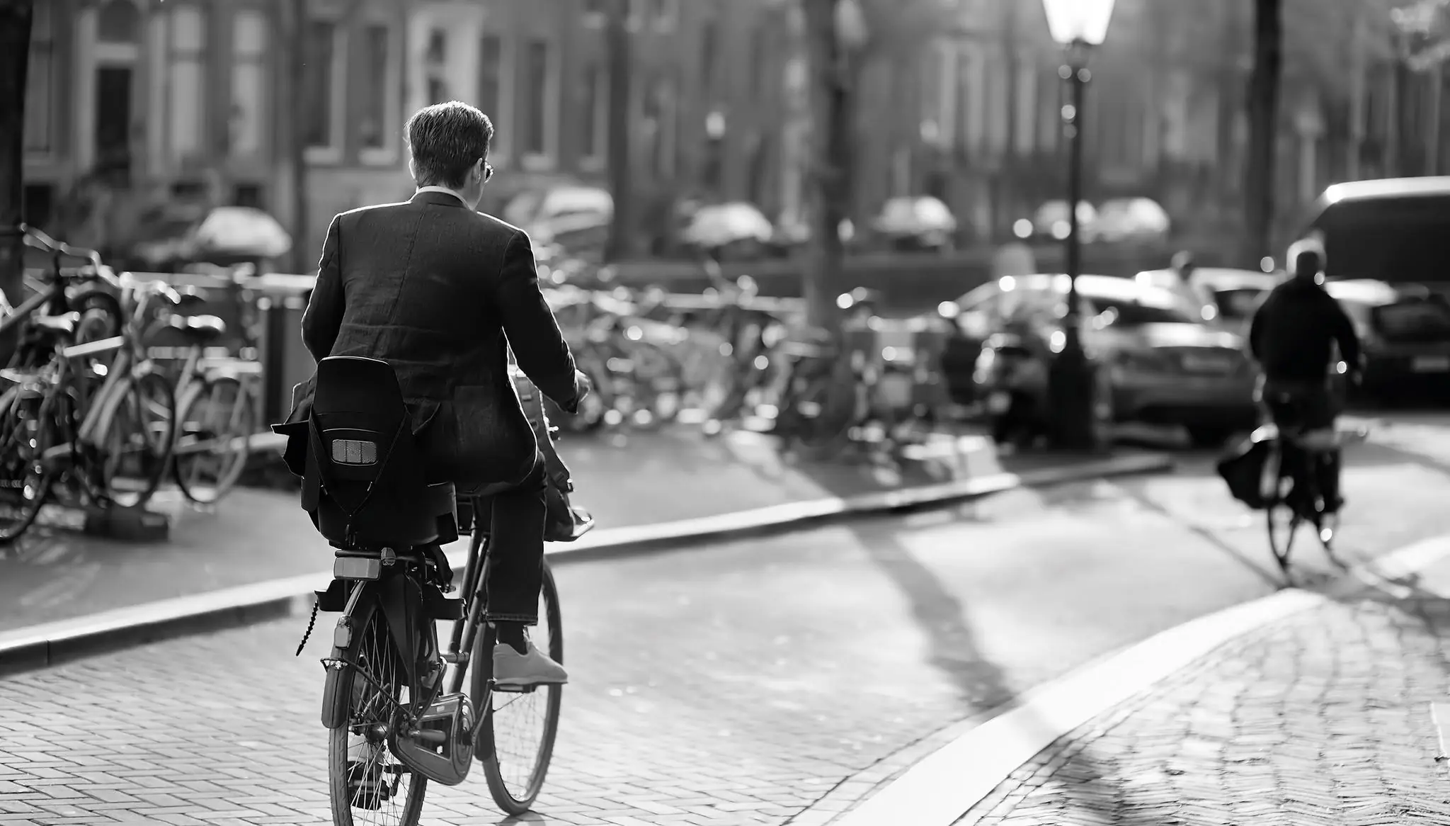 Man in pak fietst over de Vijzelgracht in Amsterdam op een zonnige dag.