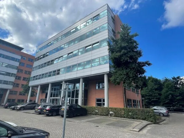 Kantoorgebouw met rode bakstenen en grijze gevelpanelen aan de Entrada 500 in Amsterdam, met geparkeerde auto's ervoor.