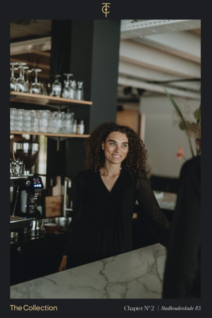 Vriendelijke barista staat achter een marmeren balie in een stijlvol café aan de Stadhouderskade.
