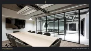 Moderne vergaderruimte aan de Stadhouderskade 85 met glazen wand, grote tafel, stoelen en flatscreen.