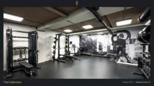 Moderne fitnessruimte aan de Stadhouderskade 85 met krachtapparatuur en een muurschildering van Amsterdamse grachtenpanden.