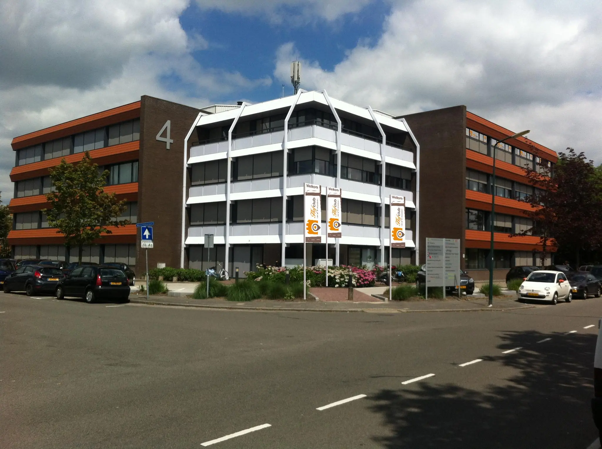 Kantoorgebouw aan de Zaagmolenlaan met nummer 4 op de gevel en drie welkomstvlaggen voor de ingang.