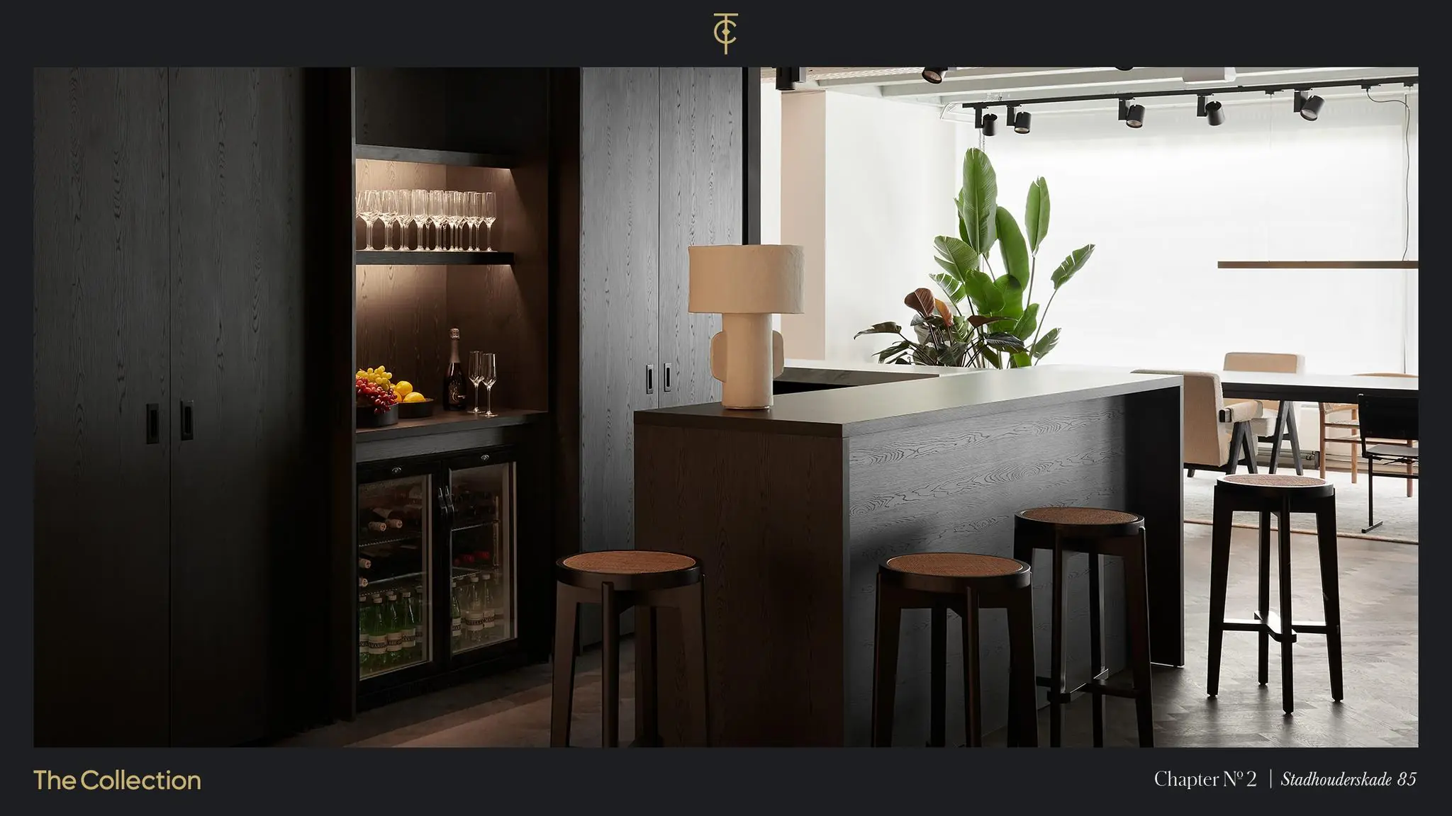 Moderne kitchenette en bar met donkere houtafwerking, barkrukken en een minimalistisch interieur aan de Stadhouderskade 85.