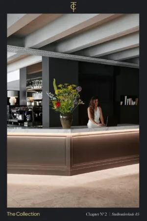 Moderne receptiebalie met marmeren blad, grote vaas met bloemen en een vrouw achter een laptop in Stadhouderskade 85.