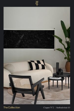 Modern ingerichte zithoek met een crèmekleurige bank, zwarte accenten en een grote groene plant, gepresenteerd in The Collection op Stadhouderskade 85.