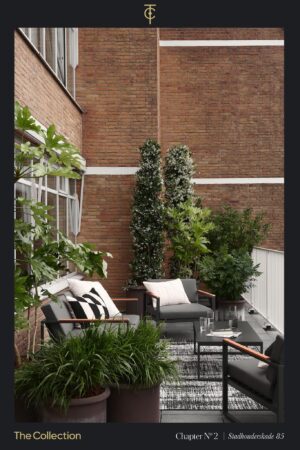 Stijlvol ingericht terras op Stadhouderskade 85 met moderne lounge meubels en weelderige planten tegen een bakstenen gevel.
