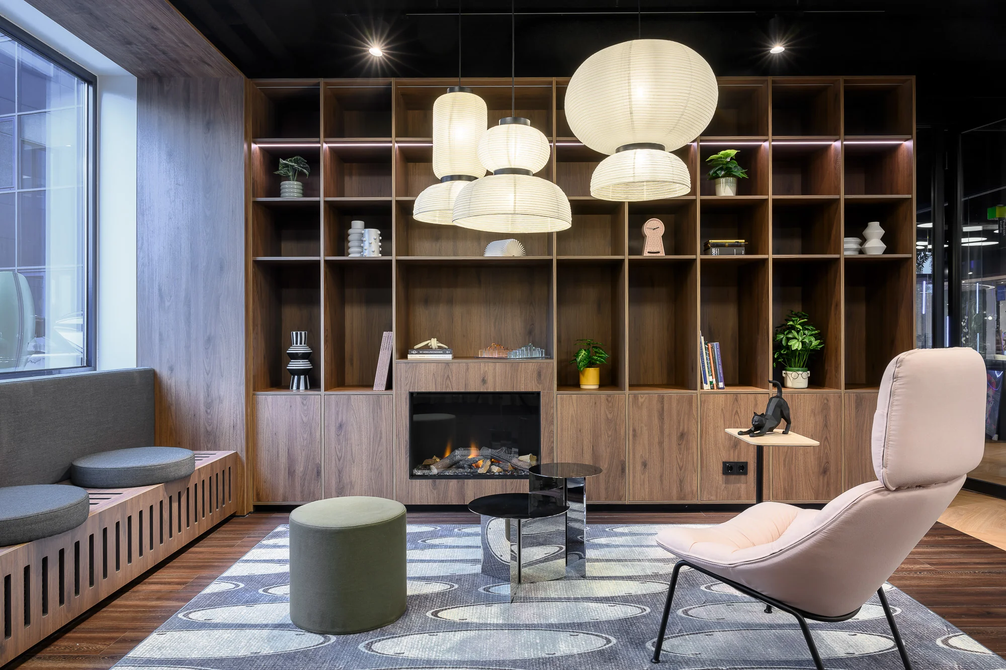 Modern ingerichte lounge met houten wandkast, open haard, designmeubilair en hanglampen.