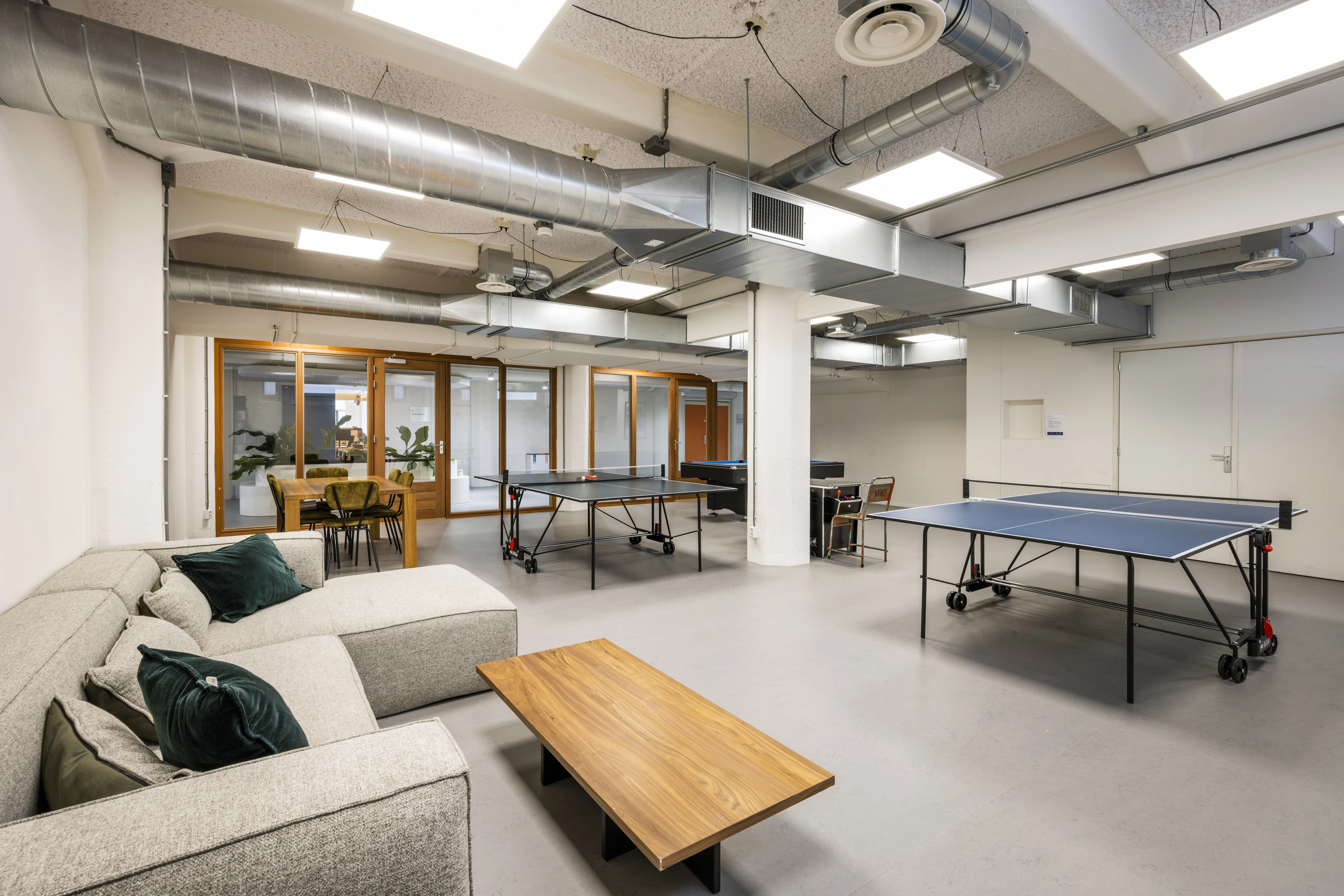 Moderne ontspanningsruimte in HNK Amsterdam Houthavens met zitbank, tafeltennistafels en vergaderruimte.