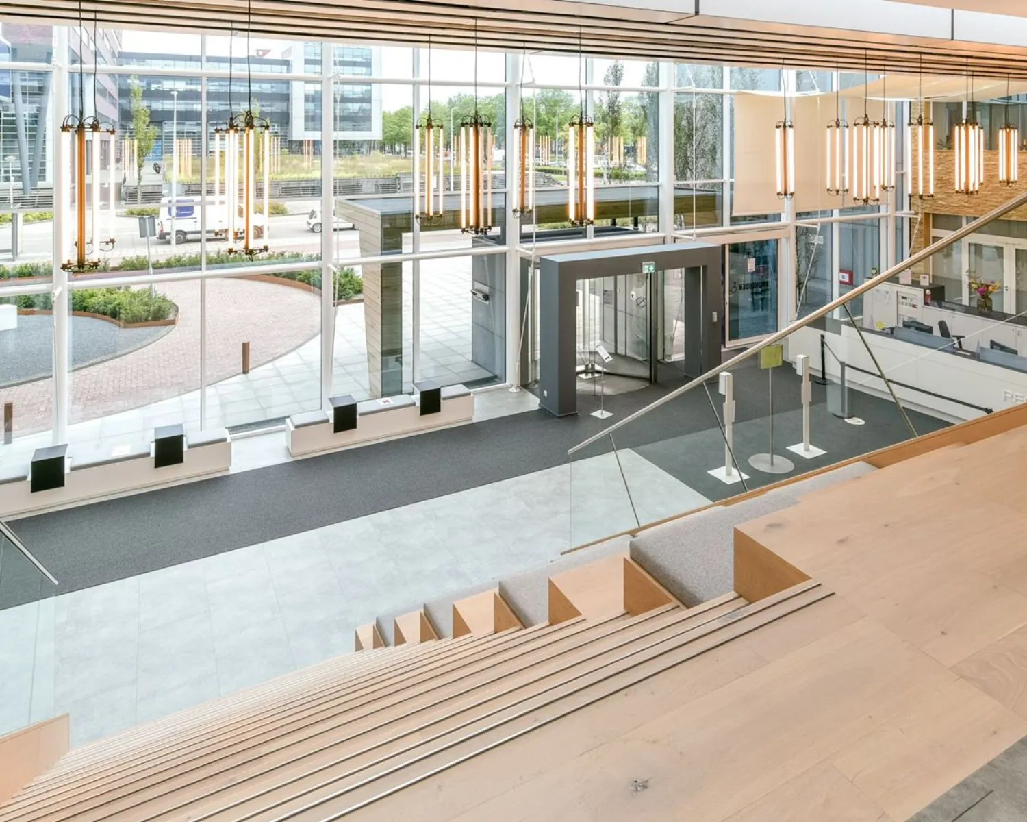 Moderne entreehal van het Coengebouw aan de Kabelweg 37 in Amsterdam met houten zithoeken, glazen wanden en hangende verlichting.