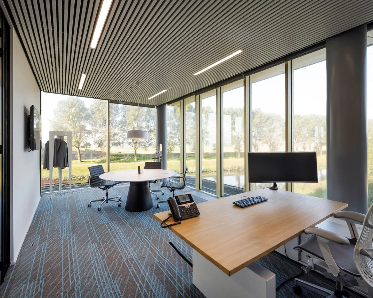 Moderne kantoorruimte met werkplek en vergadertafel aan de Taurusavenue 165 in Hoofddorp, met uitzicht op groen en water.