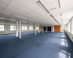 Ruime, lege kantoorruimte met blauwe vloerbedekking en veel daglicht in Entrada 300 in Amsterdam.