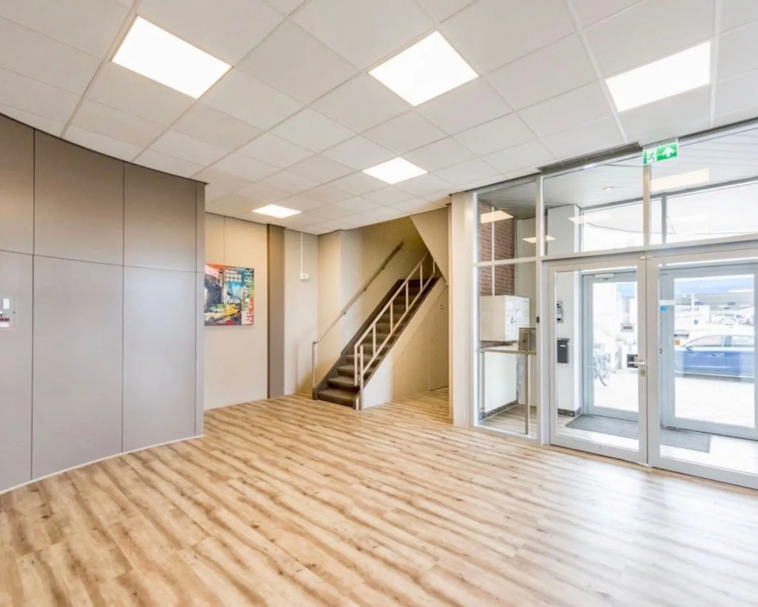 Moderne entreehal van een kantoorruimte aan de Kamerlingh Onnesweg 10 in Barendrecht met houten vloer, trap en glazen entree.