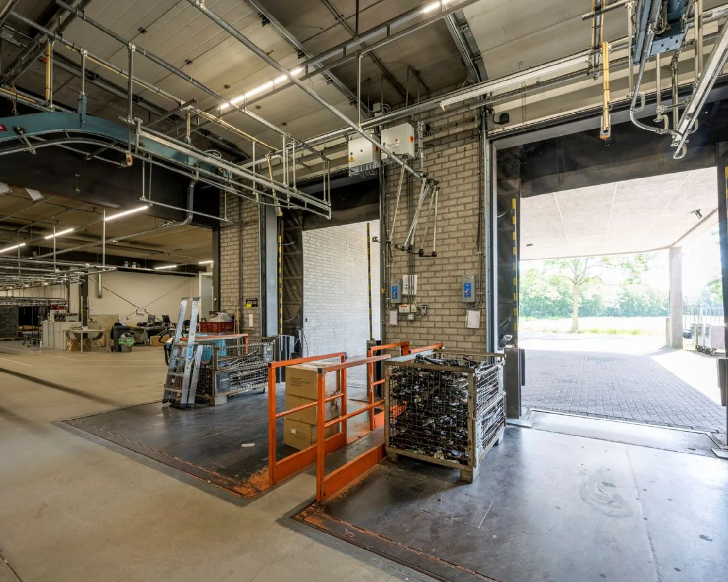 Ruime industriële laad- en losruimte in een bedrijfsgebouw aan Stammerhove 1 in Diemen met groot overheaddeur en interne opslagrekken.