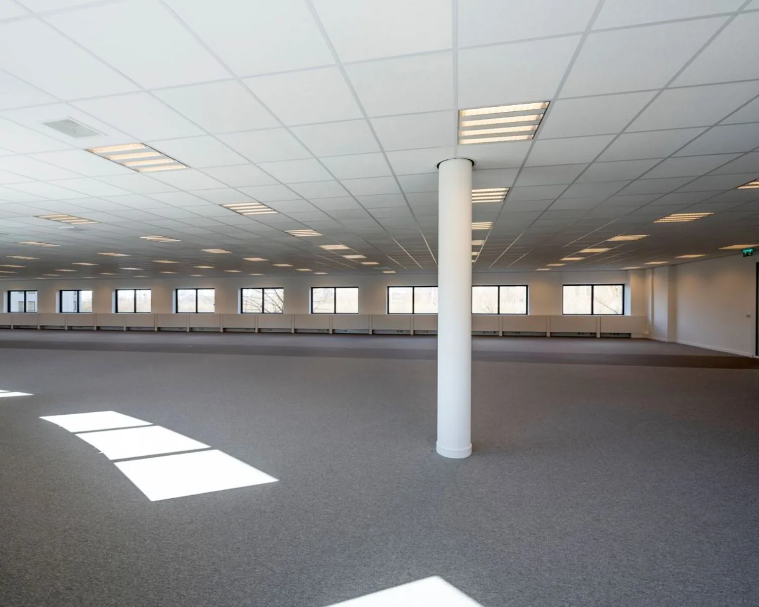 Ruime, lege kantoorruimte met systeemplafond en grote ramen aan de Wegalaan 35 in Hoofddorp.