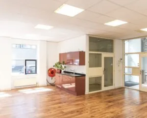 Moderne, lichte kantoorruimte aan de Wilhelminastraat 43A in Haarlem met houten vloer, pantry en grote ramen.
