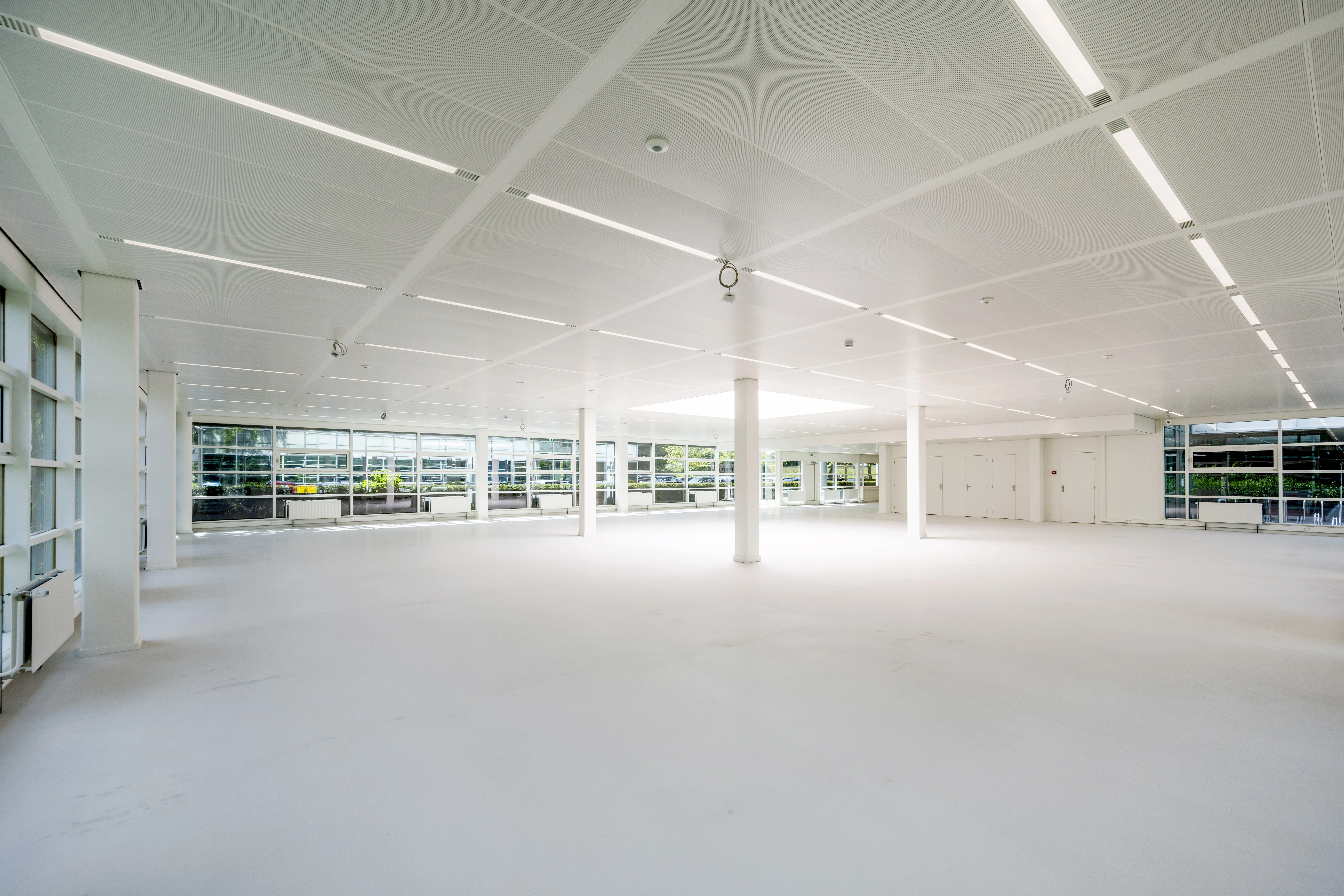 Lichte, open kantoorruimte in Amsterdam Zuidoost met grote ramen en een strak wit interieur, ontworpen door Paul Starink.