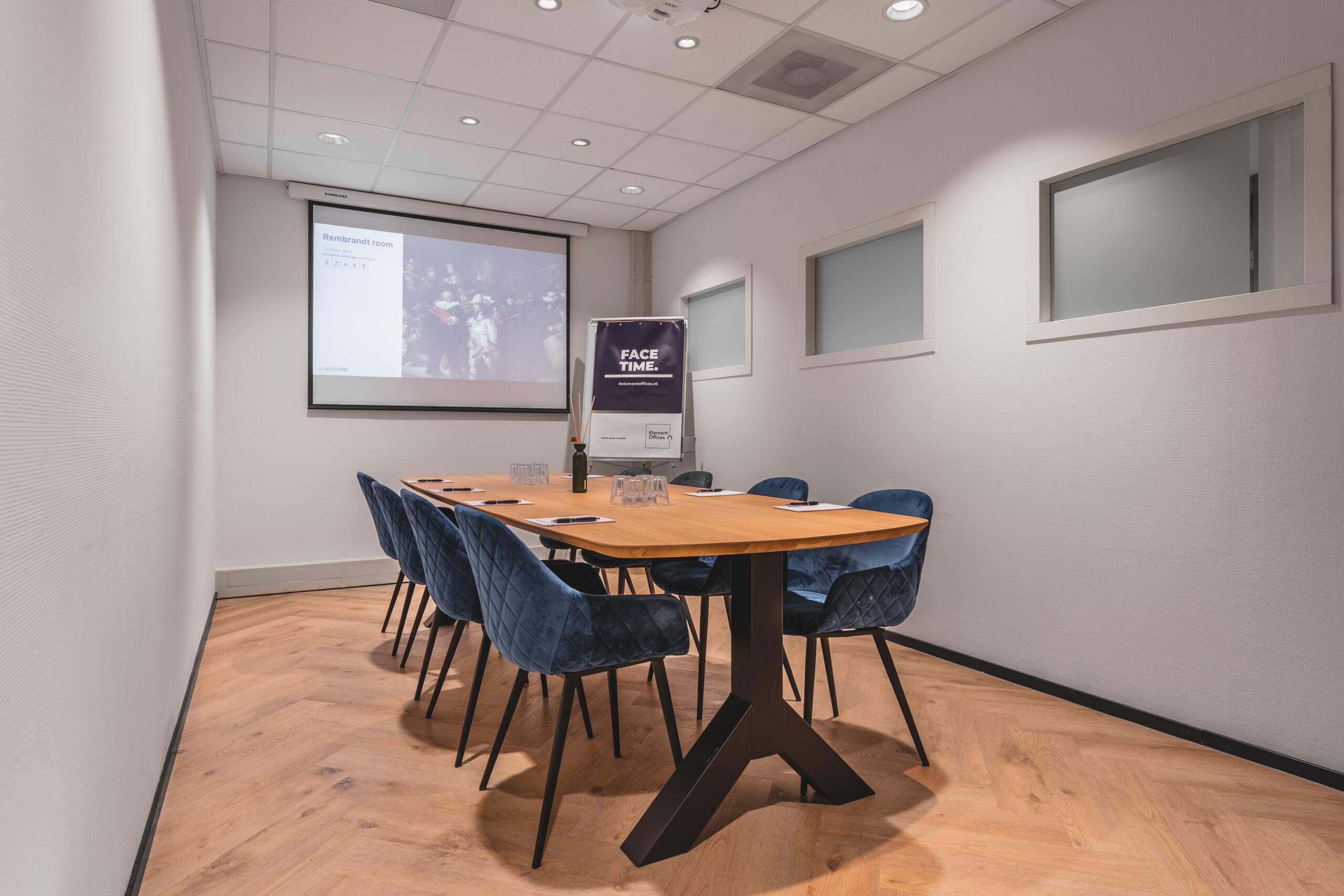 Een vergaderruimte met een grote tafel en stoelen, een presentatie op het scherm en een banner met de tekst "FACE TIME."