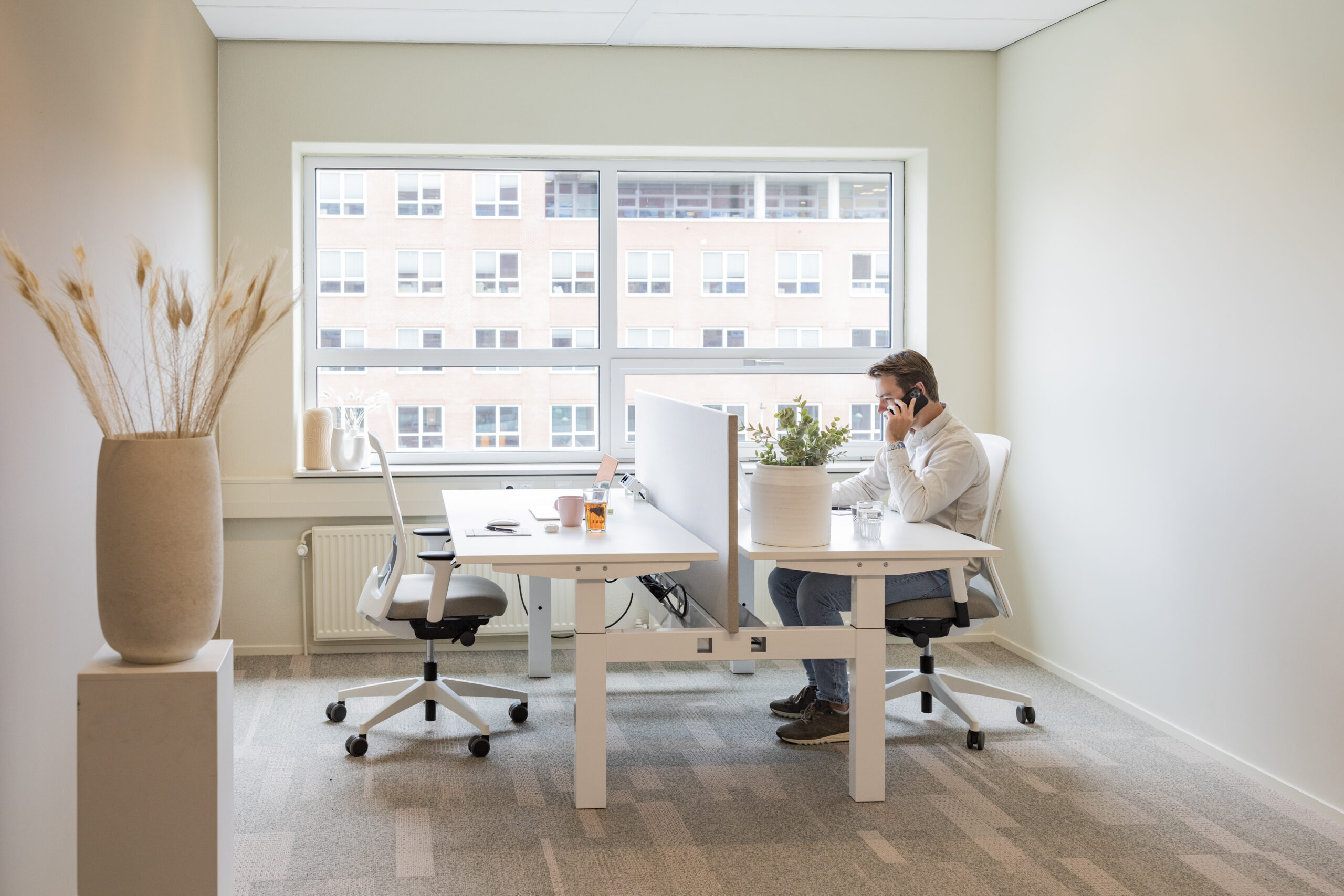 Een man zit in een modern kantoor aan een bureau en voert een telefoongesprek.